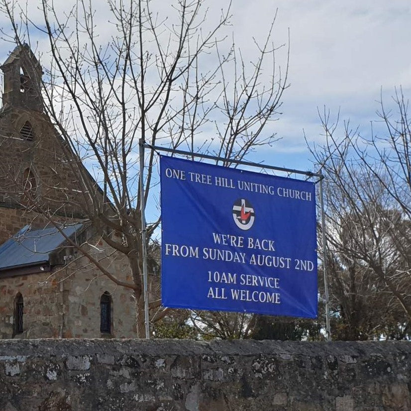 Blue outdoor banner with logo suspended by 4 eyelets in front of church